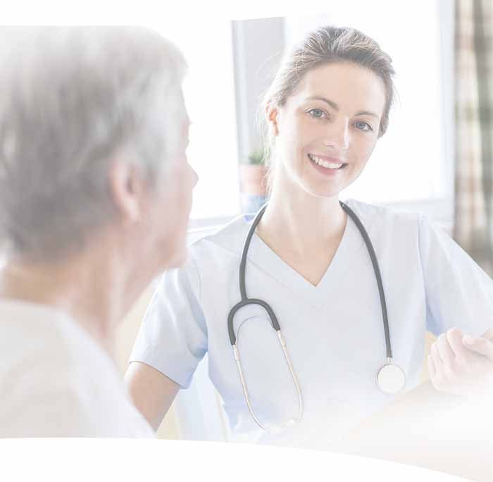 Pflegekraft im Gespräch mit einer älteren Patientin